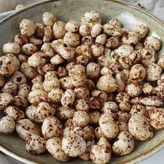 a white bowl filled with lots of brown speckled nuts on top of a table