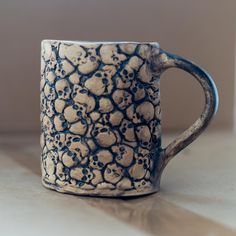 a ceramic mug with skulls on it sitting on a table