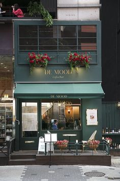 the outside of a restaurant with flowers on the windows