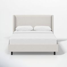 a bed with white sheets and pillows on it's headboard, in front of a wall