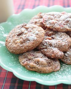 a pile of cookies on a green plate next to a glass of milk