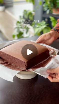 someone is cutting into a chocolate cake on a table