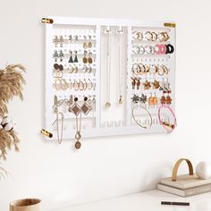 a white wall mounted jewelry rack with lots of earrings