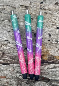 three pens sitting on top of a wooden table