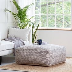 a living room with a white couch, blue and white ottoman and potted plant