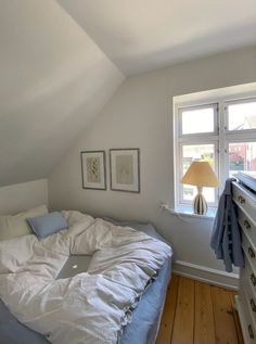 an unmade bed sitting under a window in a bedroom