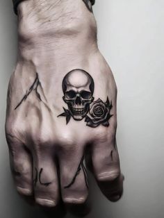 a hand with a skull and rose tattoo on it