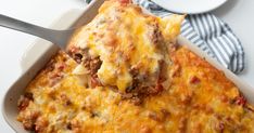 a casserole dish with meat and cheese in it on a white plate next to a fork