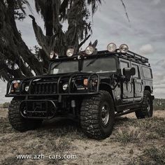 a black hummer truck parked in front of a tree with four lights on it