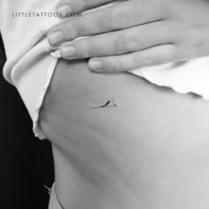 a woman's stomach with a small bird tattoo on the side of her belly