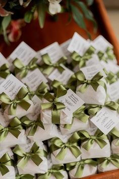 a bunch of small green bows sitting on top of each other in a wooden box