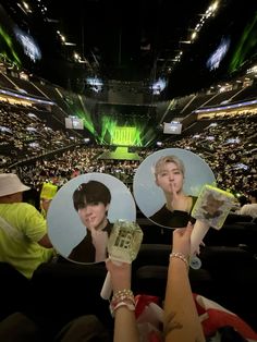 two people holding up their cell phones in front of an audience at a sporting event