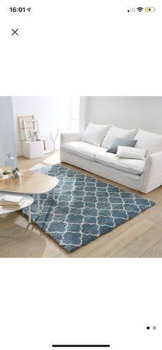 a white couch sitting on top of a wooden floor next to a blue and white rug