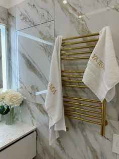 two towels hanging on the wall next to a window in a bathroom with marble walls