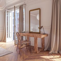 a wooden table with a mirror on top of it next to a chair and window