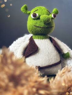 a green stuffed animal wearing a sweater and scarf