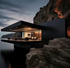 a house on the edge of a body of water with mountains in the background at night