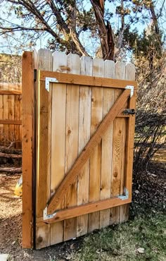 an open wooden gate in the middle of a yard