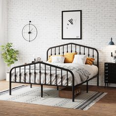 a bedroom with white brick walls and wooden flooring, a black metal bed frame