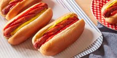 four hotdogs with ketchup and mustard on paper plates next to each other