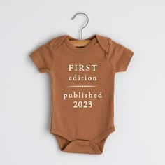 a baby bodysuit that says first edition, published in white on the front