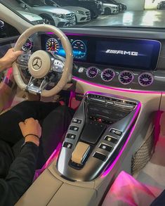 the interior of a mercedes car is lit up with pink lights and steering wheel controls