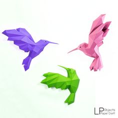 three different colored origami birds sitting on top of a white surface with one bird flying towards the other