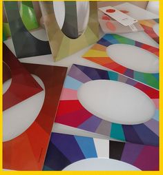 there are many different colored papers on the table together, including one with a white circle at the center