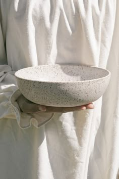 a person holding a white bowl in their left hand and wearing a white robe on the other