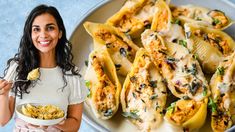 a woman holding a plate of food and smiling at the camera next to her pasta shells