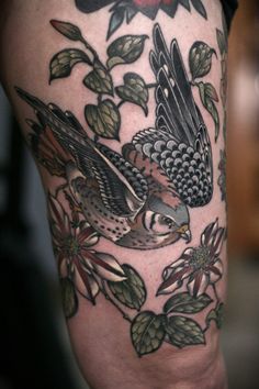 a tattoo on the leg of a woman with two birds and flowers around her legs