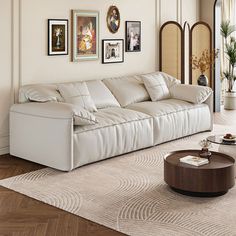 a living room with white furniture and pictures on the wall above it's coffee table