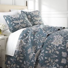 a bed with blue and white bedspread, pillows and flowers on the comforter