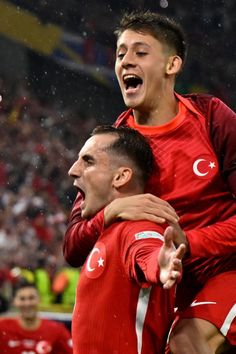 two men in red soccer uniforms are hugging each other