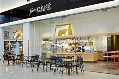 the inside of a cafe with tables and chairs in front of glass doors that read cafe