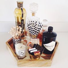 an assortment of liquor bottles on a wooden tray next to candles and other decorative items