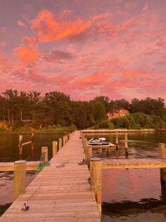 a boat is docked at the end of a wooden dock as the sun goes down