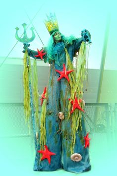 a woman dressed in blue and green with stars on her body, holding a starfish