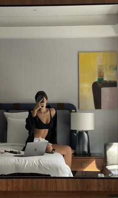 a woman sitting on top of a bed with a laptop computer next to her face