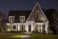 a house lit up at night with lights on the front and side of the house