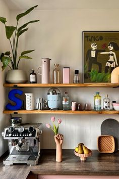 a kitchen counter topped with lots of shelves filled with food and drink bottles next to a coffee machine