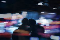 two people standing in front of a blurry city street