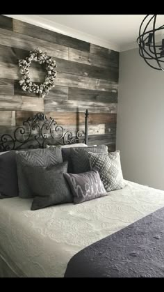 a bed with pillows and blankets on top of it in front of a wooden wall