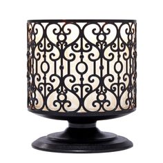 a black candle holder with an intricate design on the front and sides, holding a lit candle