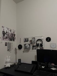 a desk with a laptop, mouse and other items on top of it in front of a white wall