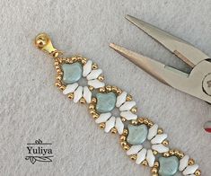 a pair of gold pliers next to a beaded bracelet with hearts on it