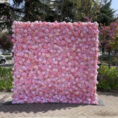 a large pink flowered wall in the middle of a sidewalk next to some trees