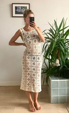 a woman taking a selfie in front of a mirror wearing a crocheted dress