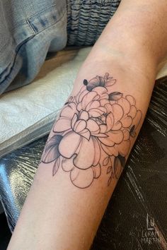 Shows an arm with fresh black linework tattoo of a peony. With black line details and shading.