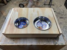 two metal bowls sitting on top of a wooden box